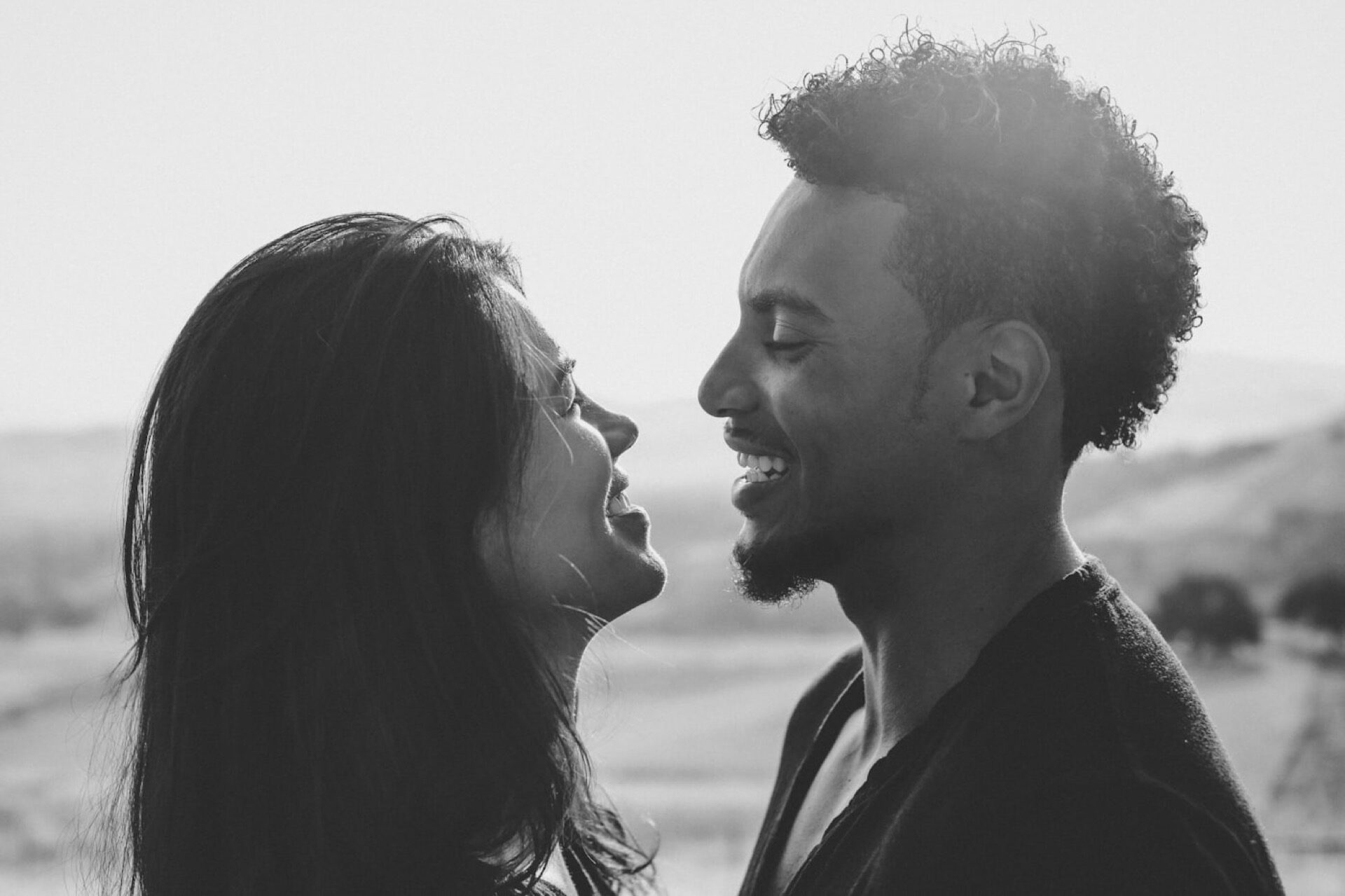 A guy and a girl sitting together on a bench overlooking the water